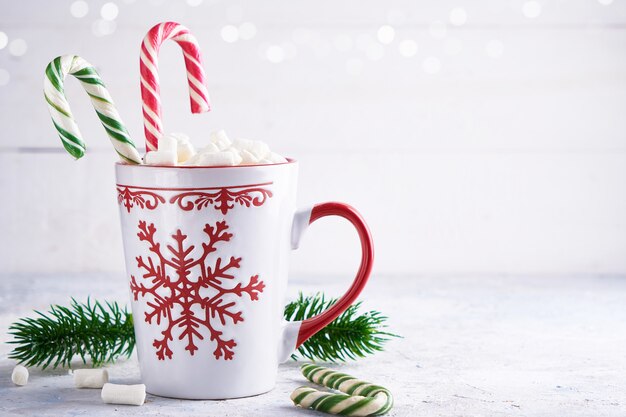 Tazza di Natale con caramelle gommosa e molle e caramelle di zucchero. Rami di abete su sfondo chiaro Copia spazio.