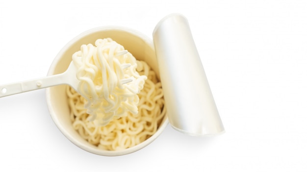 Tazza di noodles istantanei e una forchetta su uno sfondo bianco.