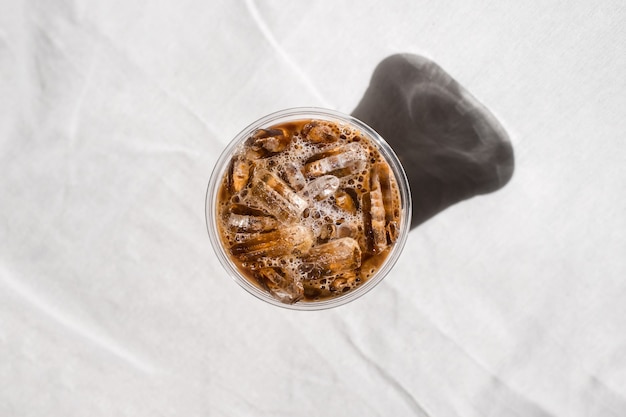 Tazza di plastica del primo piano di caffè freddo con latte sul tavolo