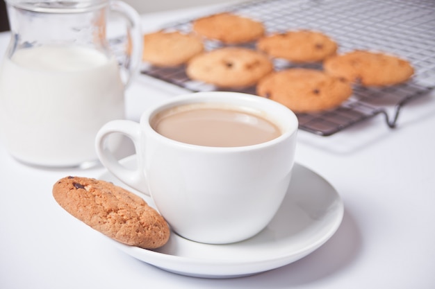 Tazza di tè al latte, biscotti fatti in casa sul bianco