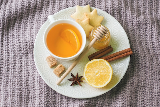 Tazza di tè al limone e biscotti, miele e bastoncini di cannella, anice stellato sulla coperta