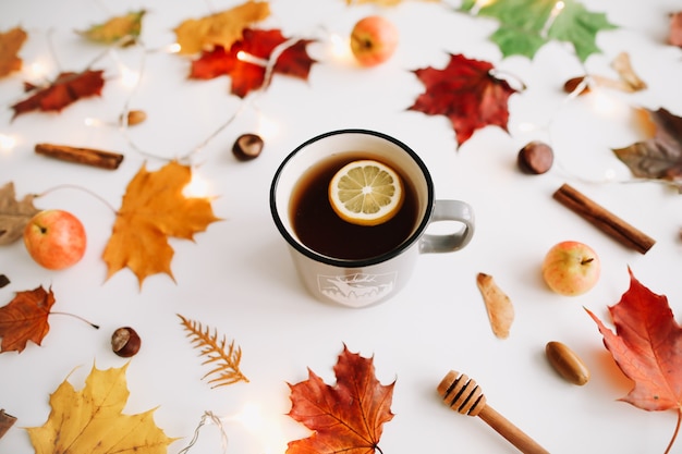 tazza di tè al limone in cornice fatta di foglie di autunno su sfondo bianco vista dall'alto spazio copia