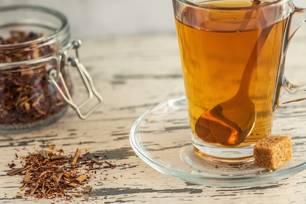 Tazza di tè al tiglio con zucchero di canna su legno grigio.