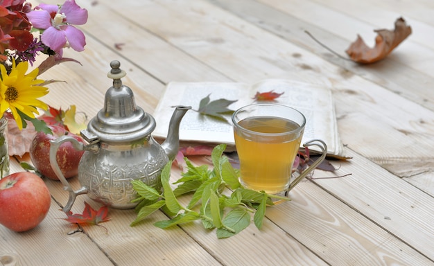 Tazza di tè alla menta con fiori e foglie di menta su un tavolo