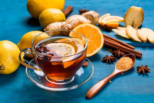 Tazza di tè allo zenzero con limone e miele su sfondo blu scuro,