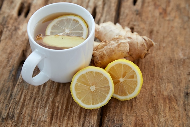 Tazza di tè allo zenzero con limone su legno