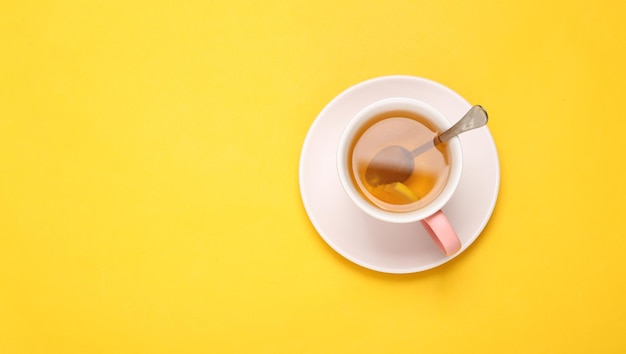Tazza di tè aromatico nero con limone su sfondo giallo Vista dall'alto Disposizione piatta Spazio di copia