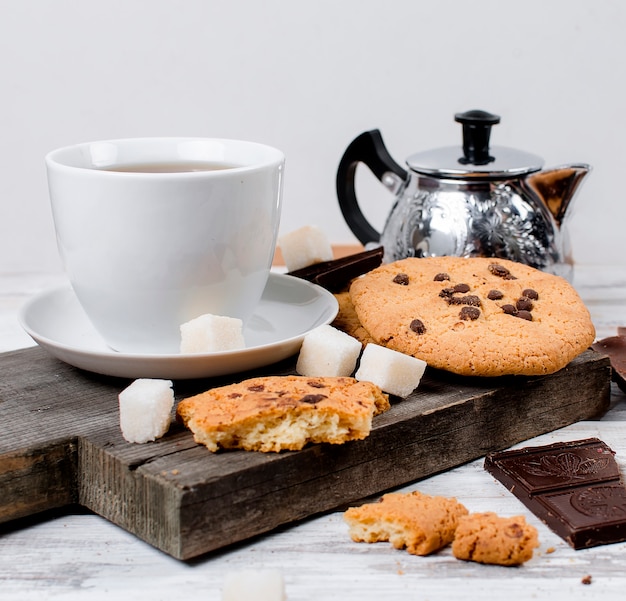 Tazza di tè, biscotti sul tavolo di legno bianco