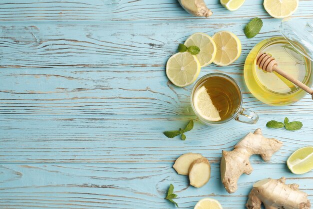 Tazza di tè caldo con miele, zenzero, limone e menta su uno sfondo di legno blu