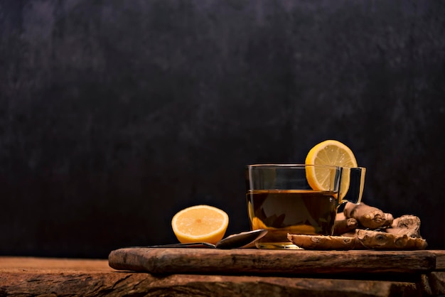 Tazza di tè caldo con radice di zenzero, limone e curcuma aggiungendo miele crudo naturale alla tazza di vitamina del tè caldo