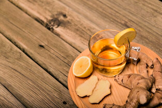 Tazza di tè caldo con radice di zenzero, limone e curcuma aggiungendo miele crudo naturale alla tazza di vitamina del tè caldo