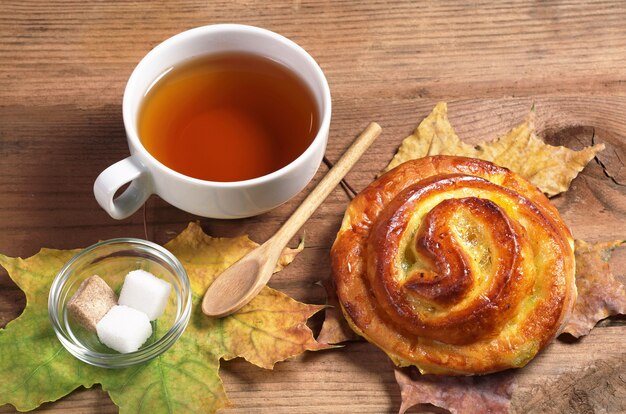 Tazza di tè caldo e panino dolce con marmellata su un vecchio tavolo di legno