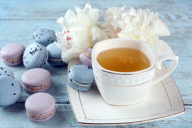 Tazza di tè con amaretti e peonie sul tavolo di legno