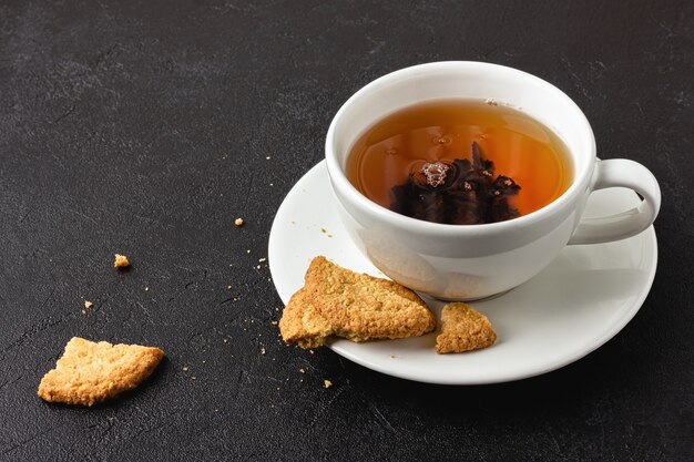 Tazza di tè con biscotti su sfondo nero. Vista laterale.