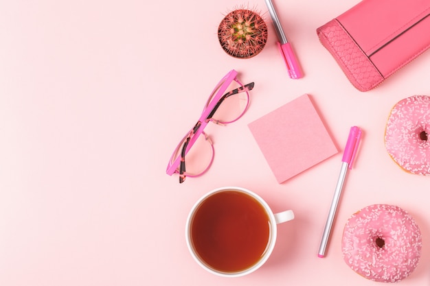 Tazza di tè con ciambelle su uno sfondo rosa pastello