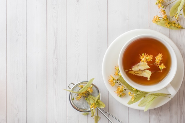 Tazza di tè con fiori di tiglio su un tavolo luminoso