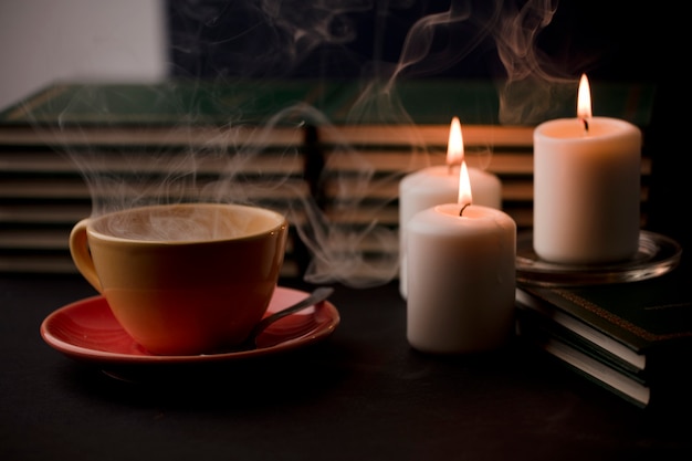 tazza di tè con fumo caldo e tre candele accese sulla scrivania a casa interruzione di corrente