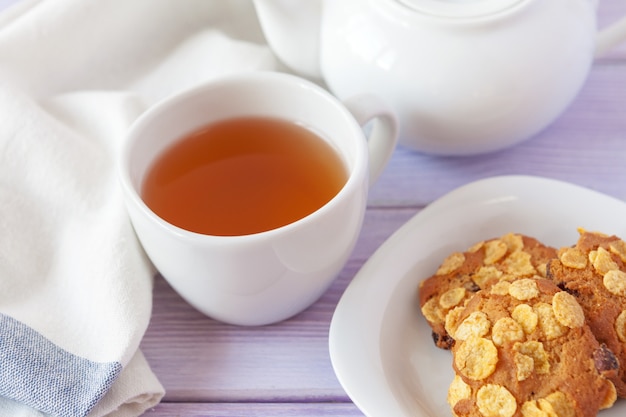 Tazza di tè con i biscotti sopra legno lilla