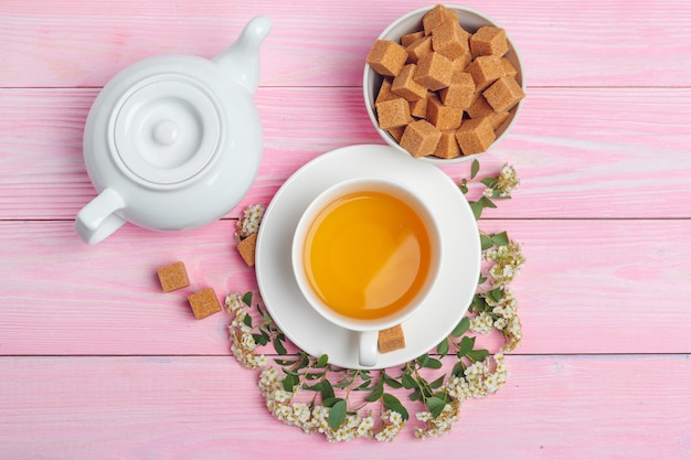 Tazza di tè con i cubi dello zucchero e rami del fiore sulla fine di legno della tavola su