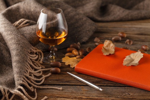 Tazza di tè con il vecchio libro, foglie di autunno sul tavolo di legno.