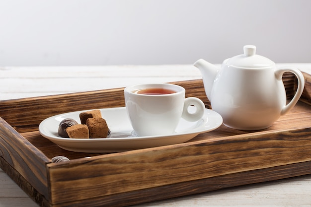 Tazza di tè con la caramella di cioccolato sulla tavola di legno