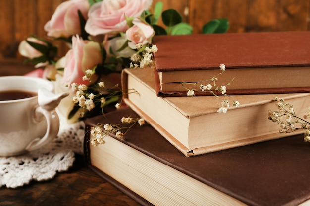 Tazza di tè con libri e fiori su fondo di legno