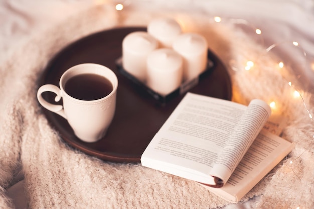 Tazza di tè con libro aperto e cavi a letto da vicino. Buon giorno.