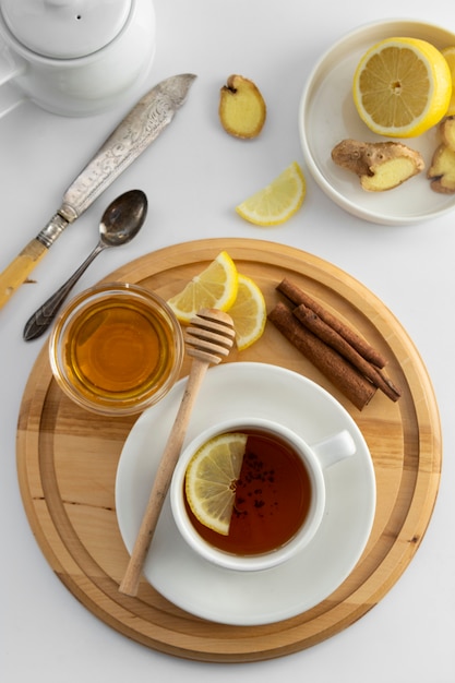 Tazza di tè con limone e miele su uno sfondo bianco