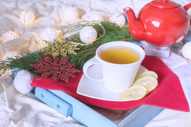 Tazza di tè con limone su un vassoio sul letto a letto comfort inverno mattina