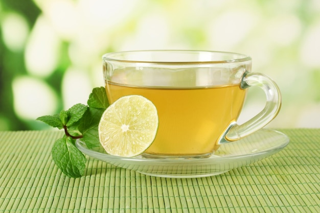 Tazza di tè con menta e lime sul tavolo su sfondo luminoso