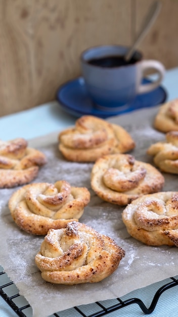 Tazza di tè e biscotti di pasta frolla fatti in casa a forma di rosa. Sfondo scuro.