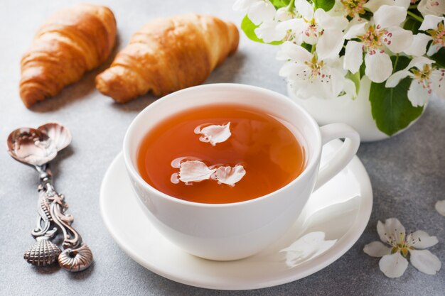 Tazza di tè e croissant su grigio