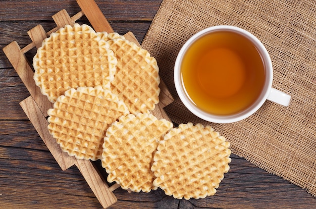 Tazza di tè e gustose cialde fatte in casa su tavola in legno rustico, vista dall'alto