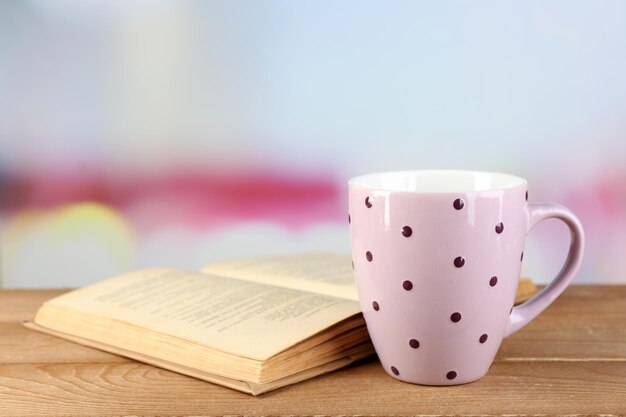 Tazza di tè e libro sul tavolo su sfondo luminoso