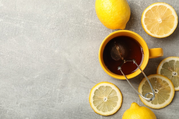 Tazza di tè e limoni su grigio, spazio per il testo