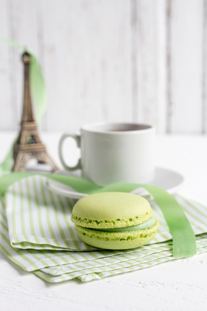 Tazza di tè e maccheroni francesi verdi su un bianco di legno