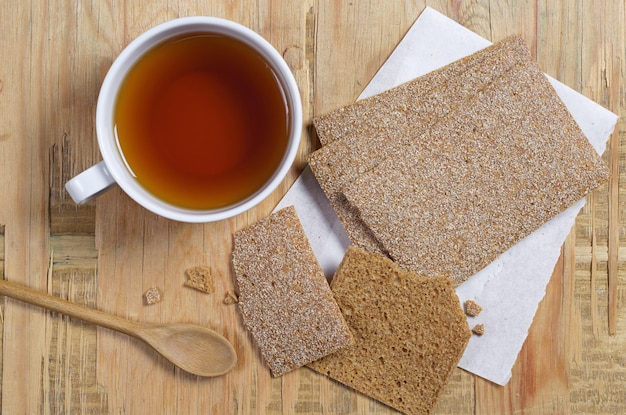 Tazza di tè e pane croccante ipocalorico su una vecchia vista dall'alto del fondo di legno