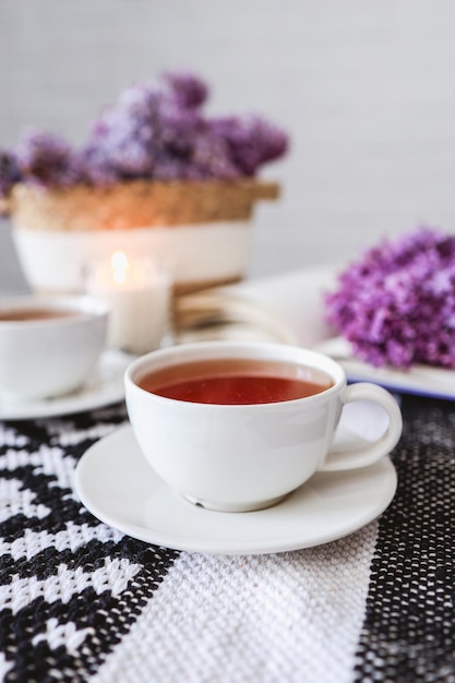 Tazza di tè e rami di lillà in fiore su tavola di legno Fotografia d'atmosfera accogliente per feste da tè