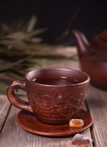 Tazza di tè e zucchero con teiera sullo sfondo