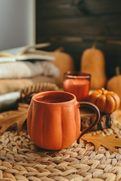 Tazza di tè fumante calda con foglie d'autunno, zucche e spezie sul davanzale Atmosfera autunnale