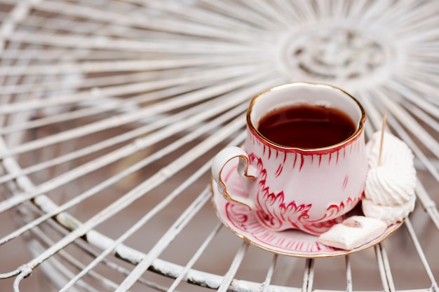 Tazza di tè in stile rustico con marshmallow sul tavolo forgiato bianco.