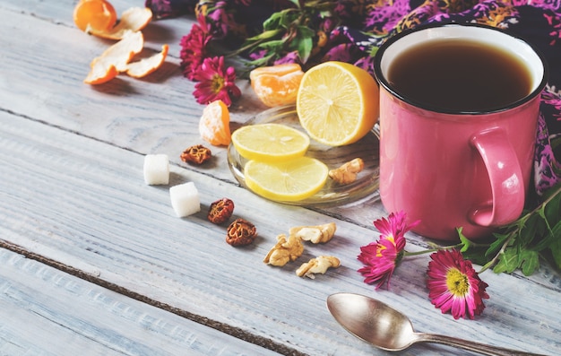 Tazza di tè, limone e fiori su un tavolo di legno bianco