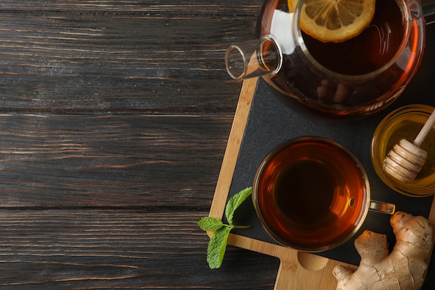 Tazza di tè, menta, miele, zenzero e teiera su legno, vista dall'alto