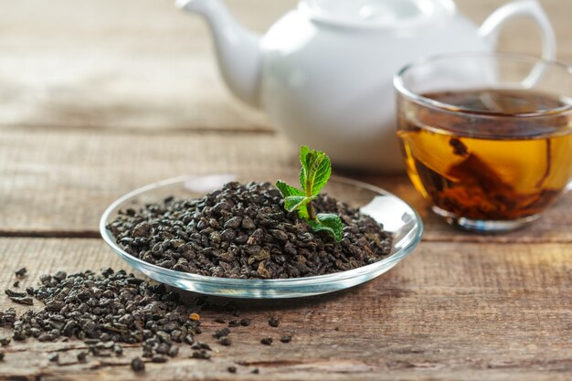 Tazza di tè nero con foglie di menta su un tavolo di legno