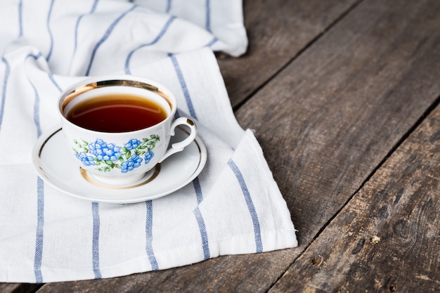 Tazza di tè nero in una tazza di porcellana e piattino