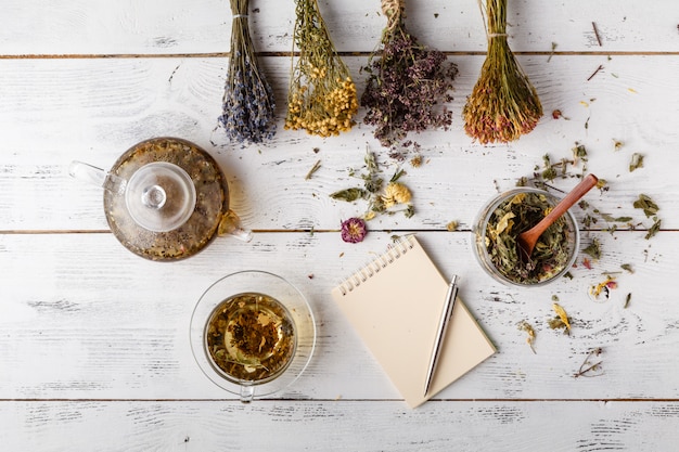 Tazza di tè sano, miele, erbe curative, assortimento di tisane e frutti di bosco sul tavolo. Vista dall'alto. Medicina di erbe.