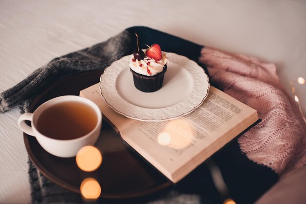 Tazza di tè verde con gustoso cupcake e libro aperto