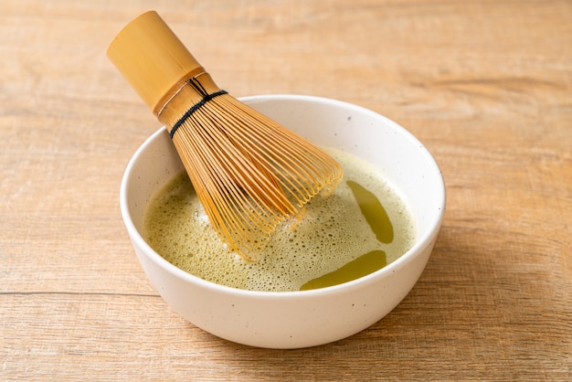 tazza di tè verde matcha calda con polvere di tè verde e frusta