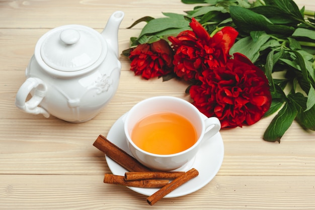 Tazza di tè verde sul tavolo con fiori di peonia freschi