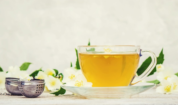 Tazza di tisana con fiori di gelsomino. messa a fuoco selettiva.